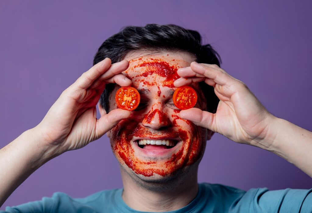 A guy with tomato paste on his face for skincare