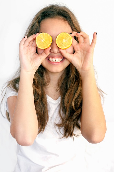 Girl covering her eyes with cut lemons