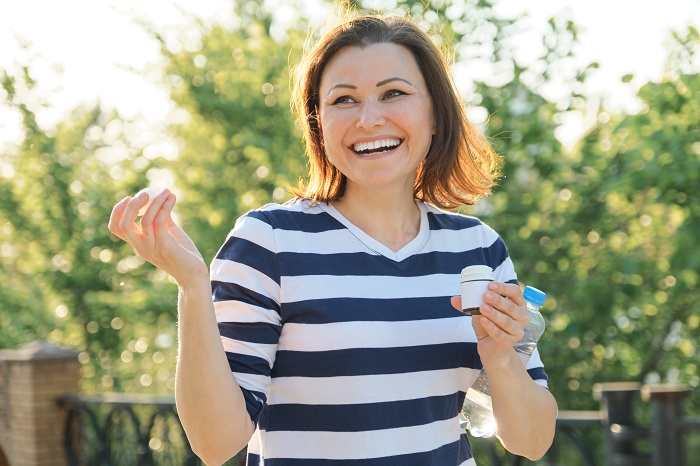Middle aged woman outdoors taking vitamins