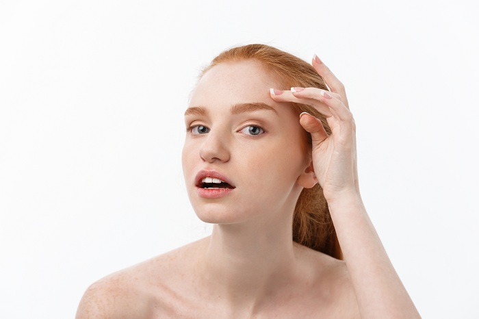 Redhead woman checking skin from irritation