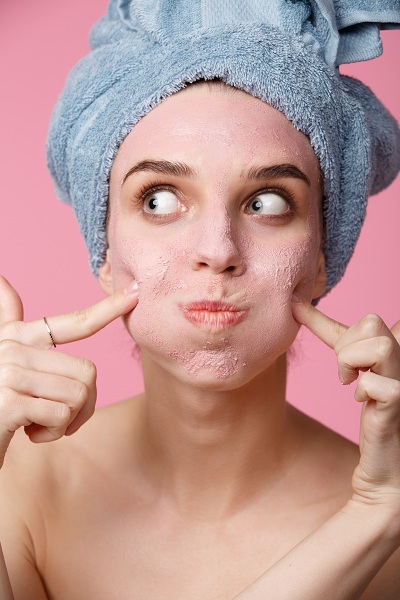 Woman applying clay face mask for treatment