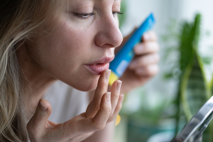 Woman applying moisturizing balm on lips