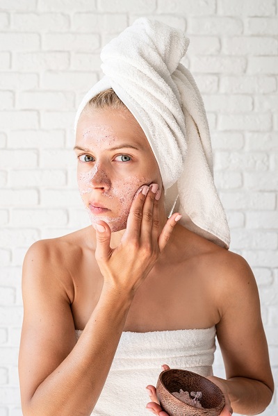 Woman in white bath towels applying face scrubs