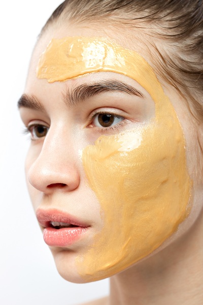 The face of a young girl with yellow cosmetic mask on it