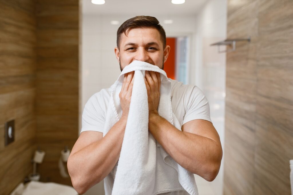 Man wipes his face with a towel