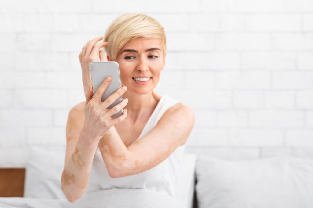 Middle-aged woman touching hair smiling looking in cellphone