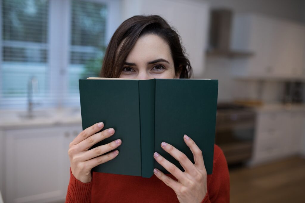 Portrait of beautiful woman covering her face with book