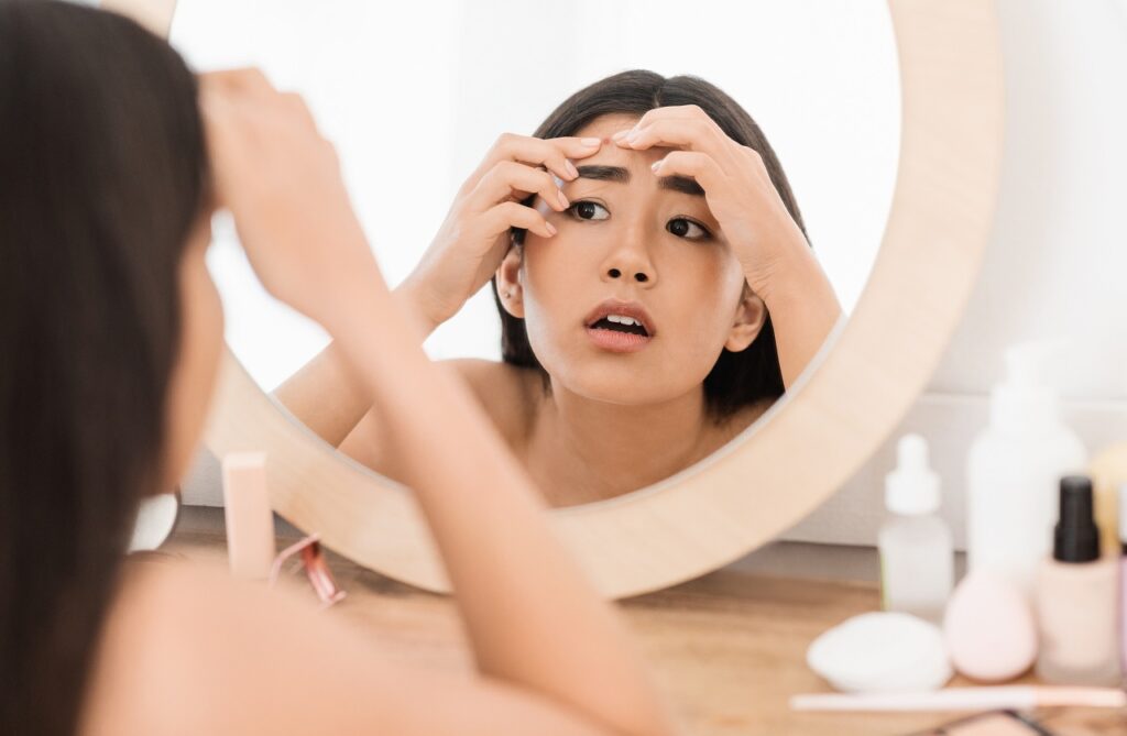 young woman checking her pimples in the mirror
